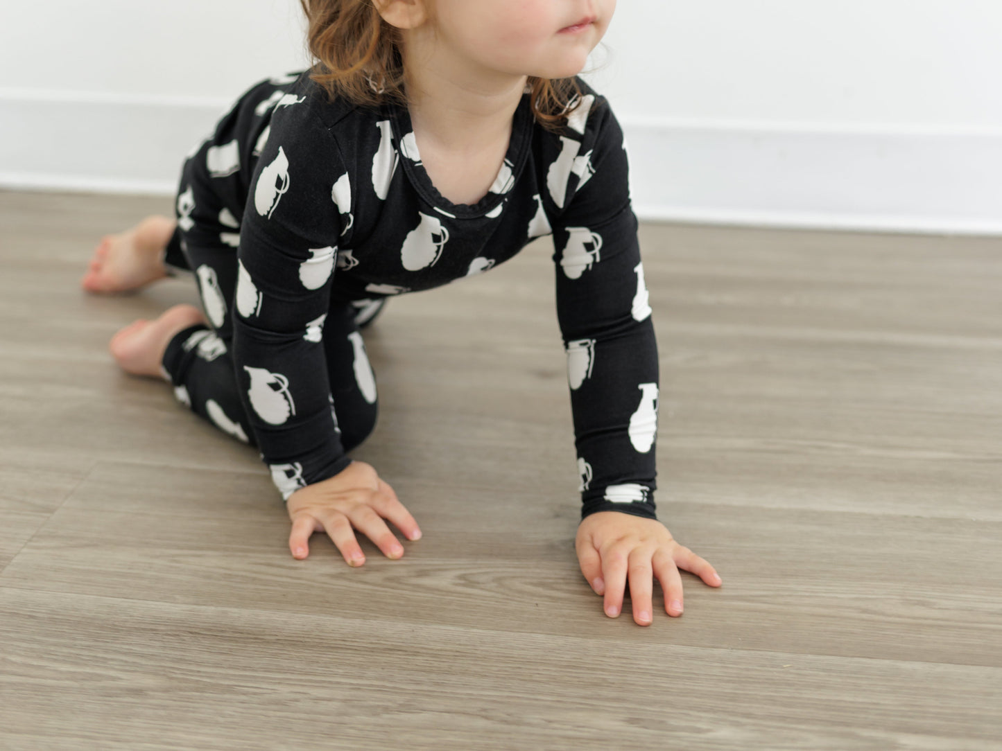Child wearing a black outfit with white patterns on a wooden floor