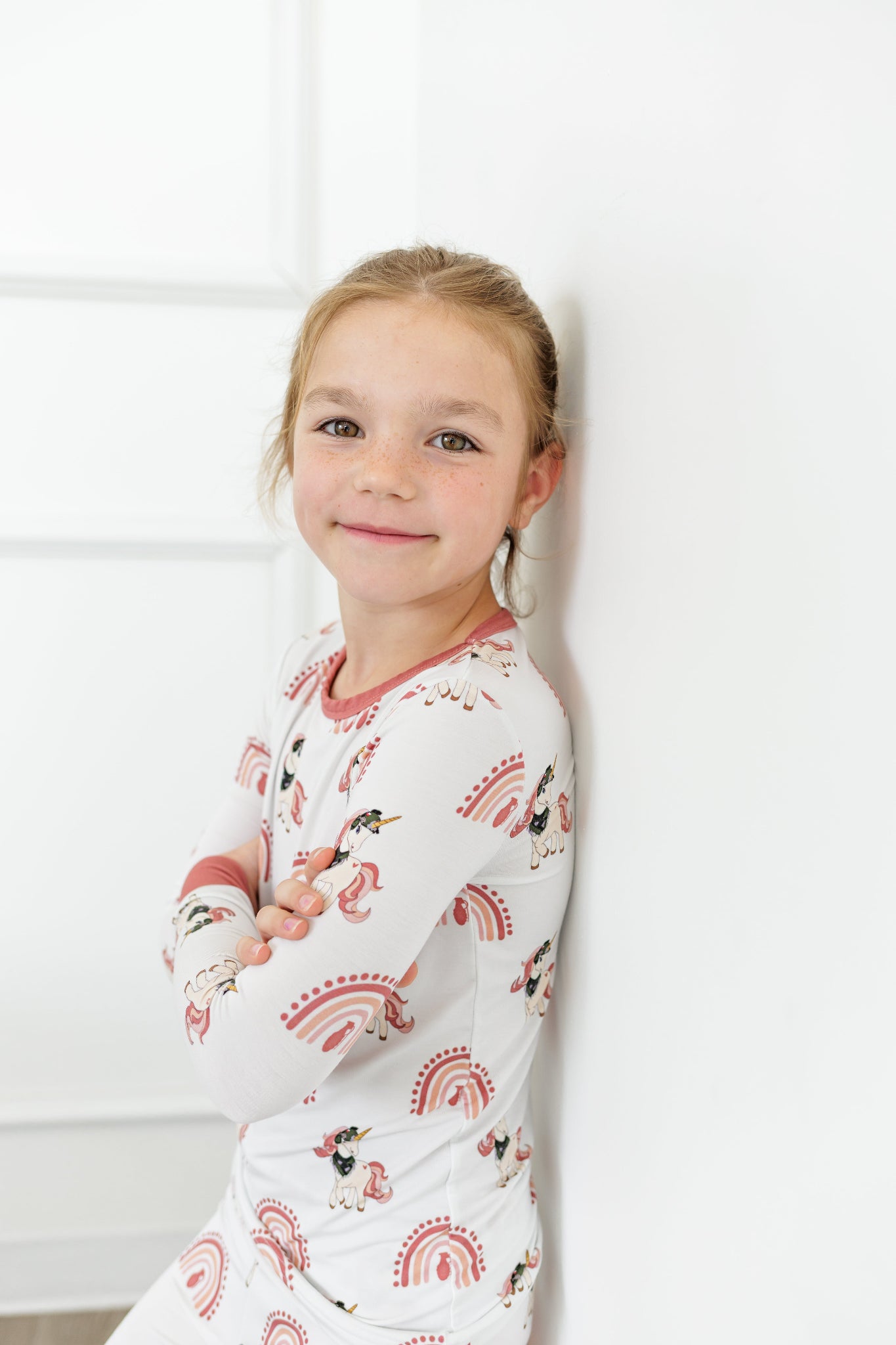 Young girl wearing a long-sleeve pajama set with animal print against a white background