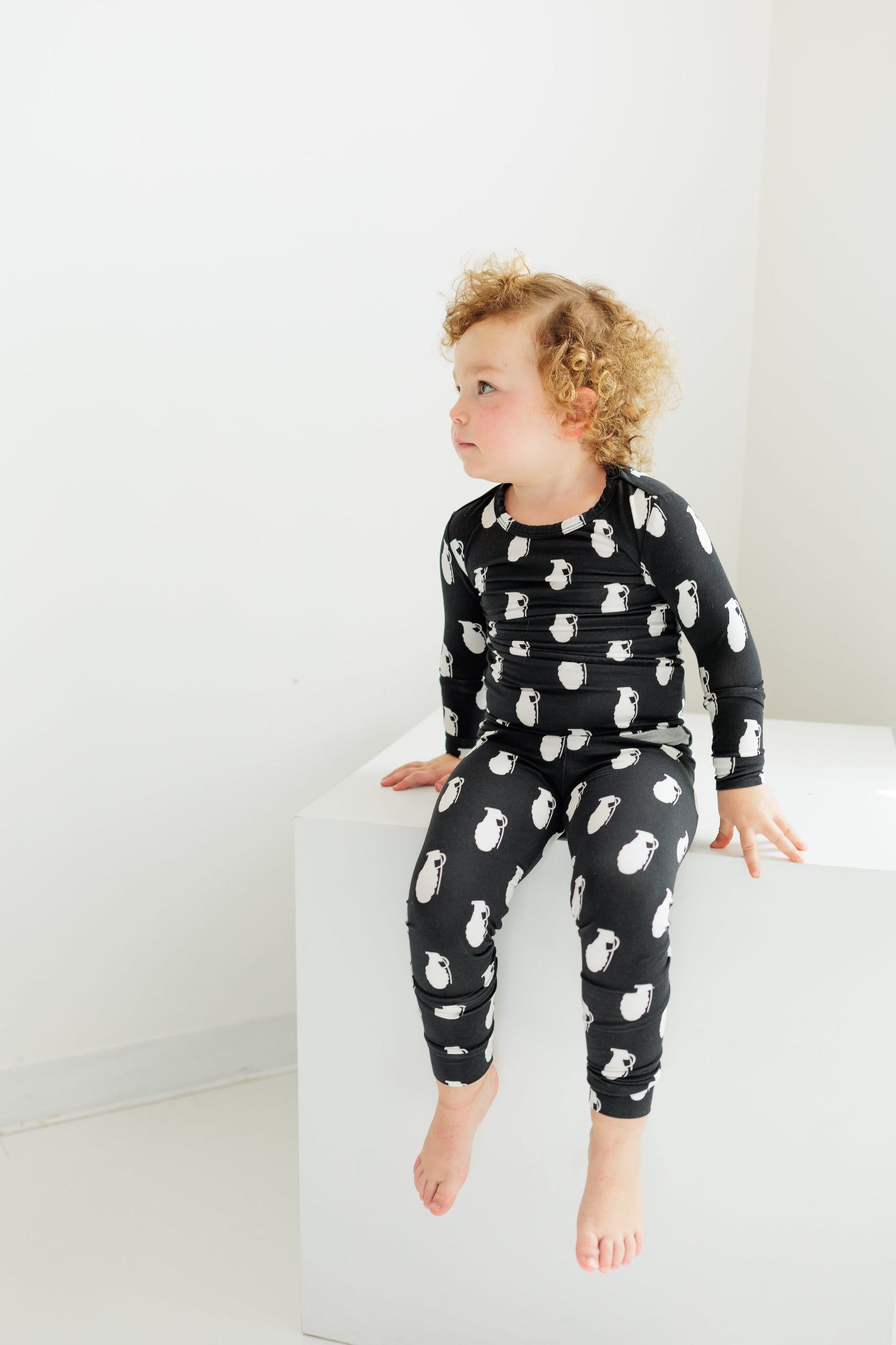 Child wearing a black pajama set with white animal prints on a white background