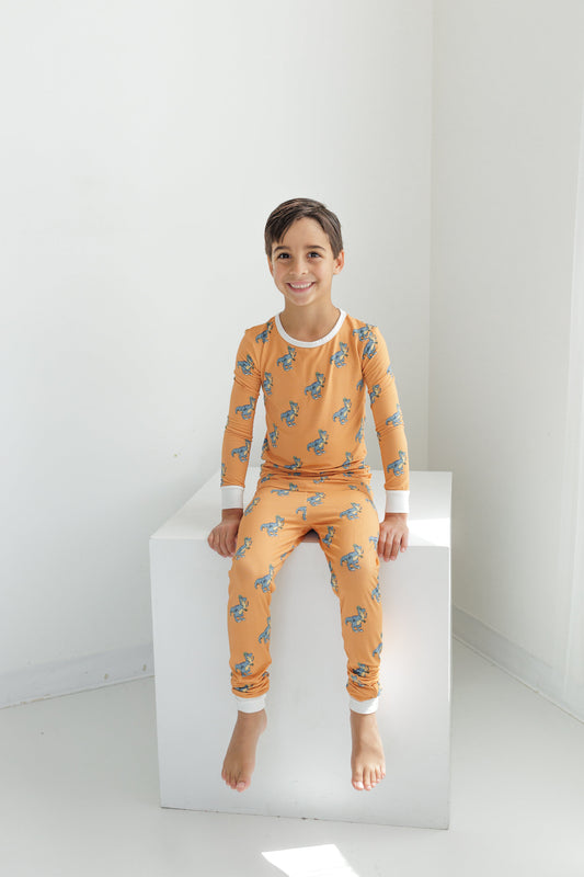 Child wearing orange pajamas with a pattern on a white background