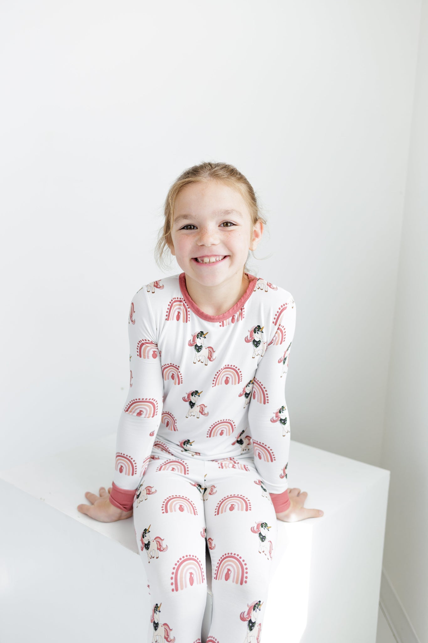 Child wearing a white pajama set with red accents and cartoon characters on a white background