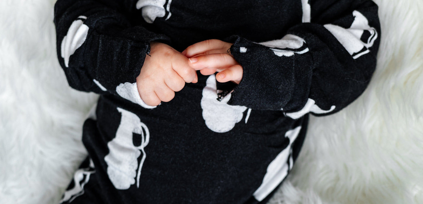 Person wearing a black and white patterned outfit on a white fluffy blanket