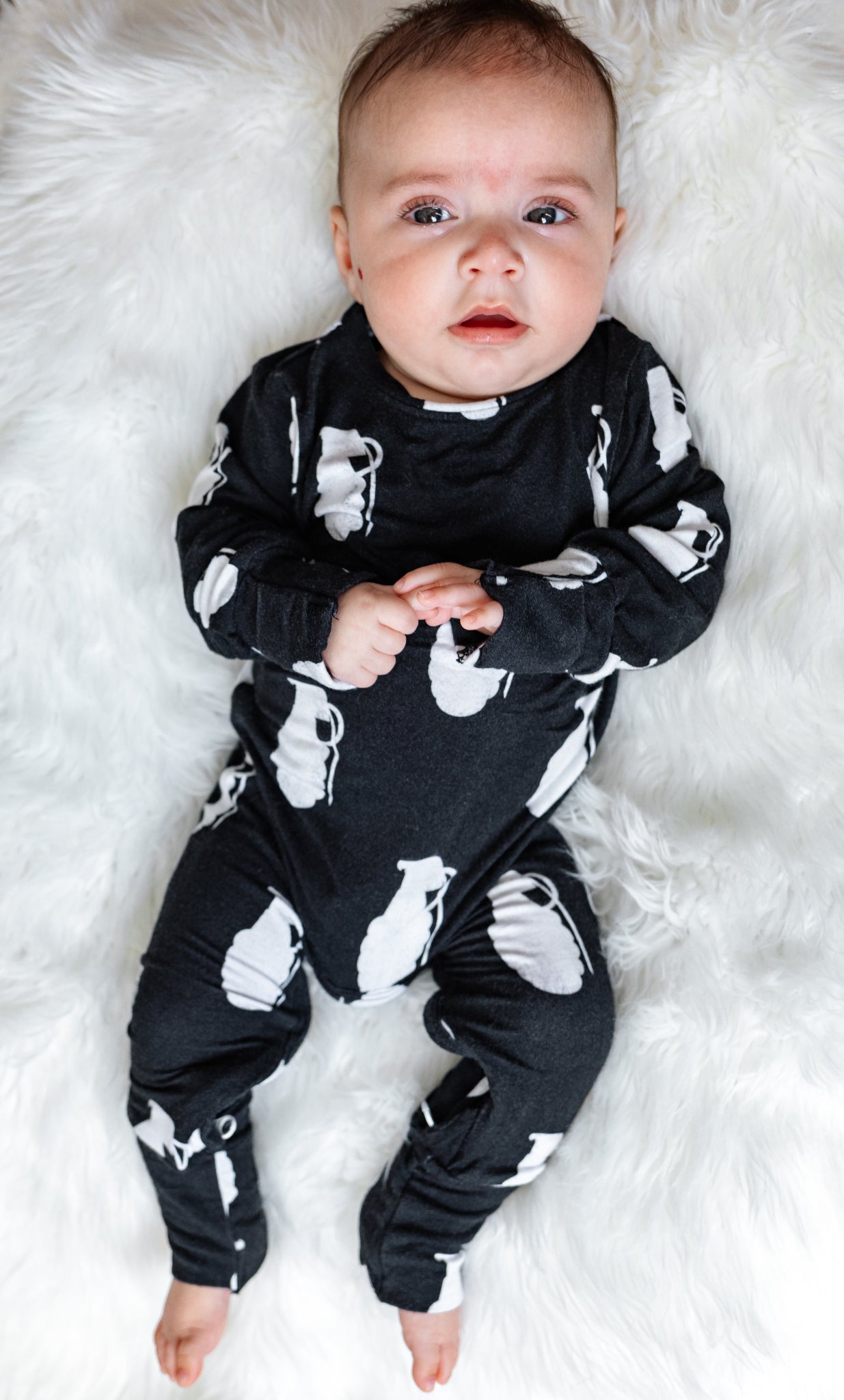 Baby wearing a black outfit with white patterns on a white fluffy surface