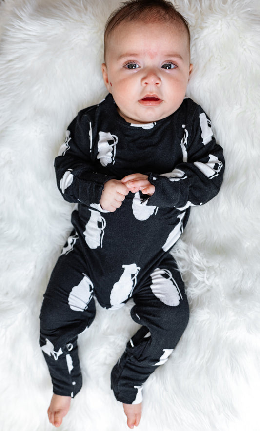 Baby wearing a black outfit with white patterns on a white fluffy surface