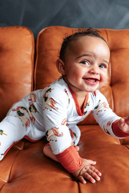 Baby in pajamas sitting on a brown leather couch