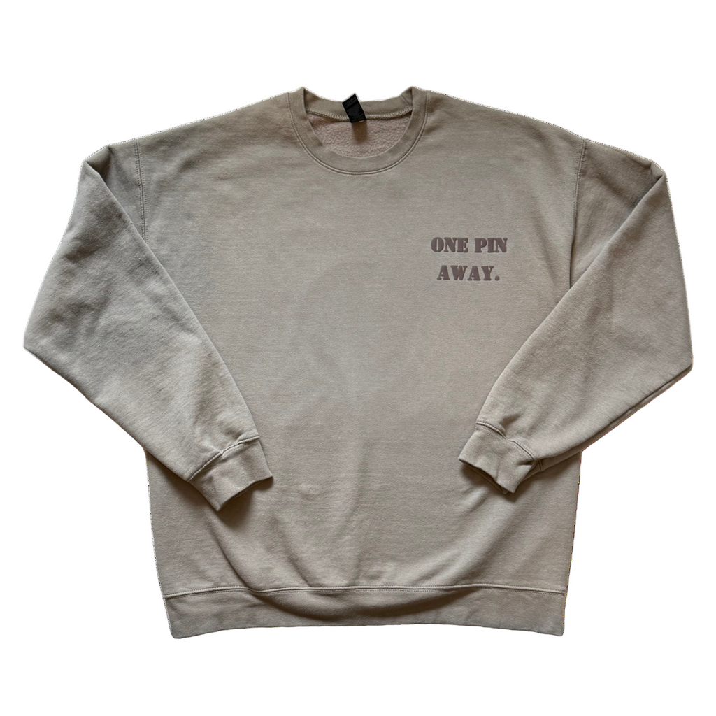 Beige sweatshirt with 'ONE PIN AWAY.' text on a white background