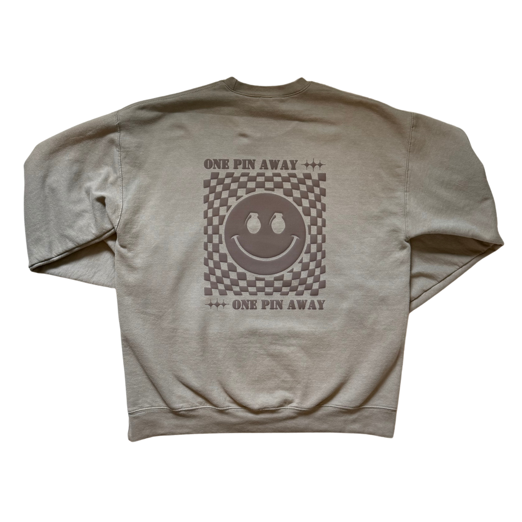 Beige sweatshirt with a smiley face design and text on the back against a white background