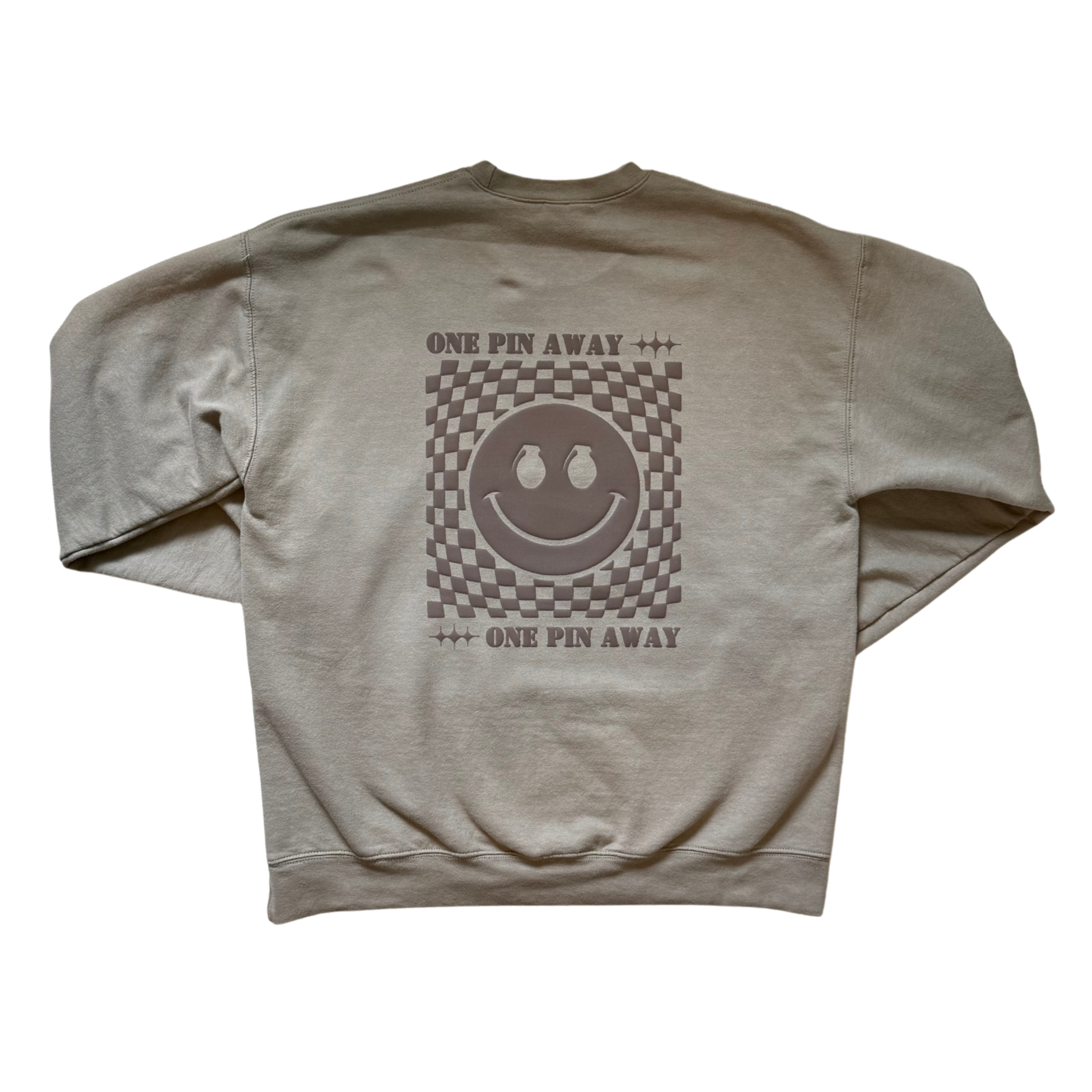 Beige sweatshirt with a smiley face design and text on the back against a white background