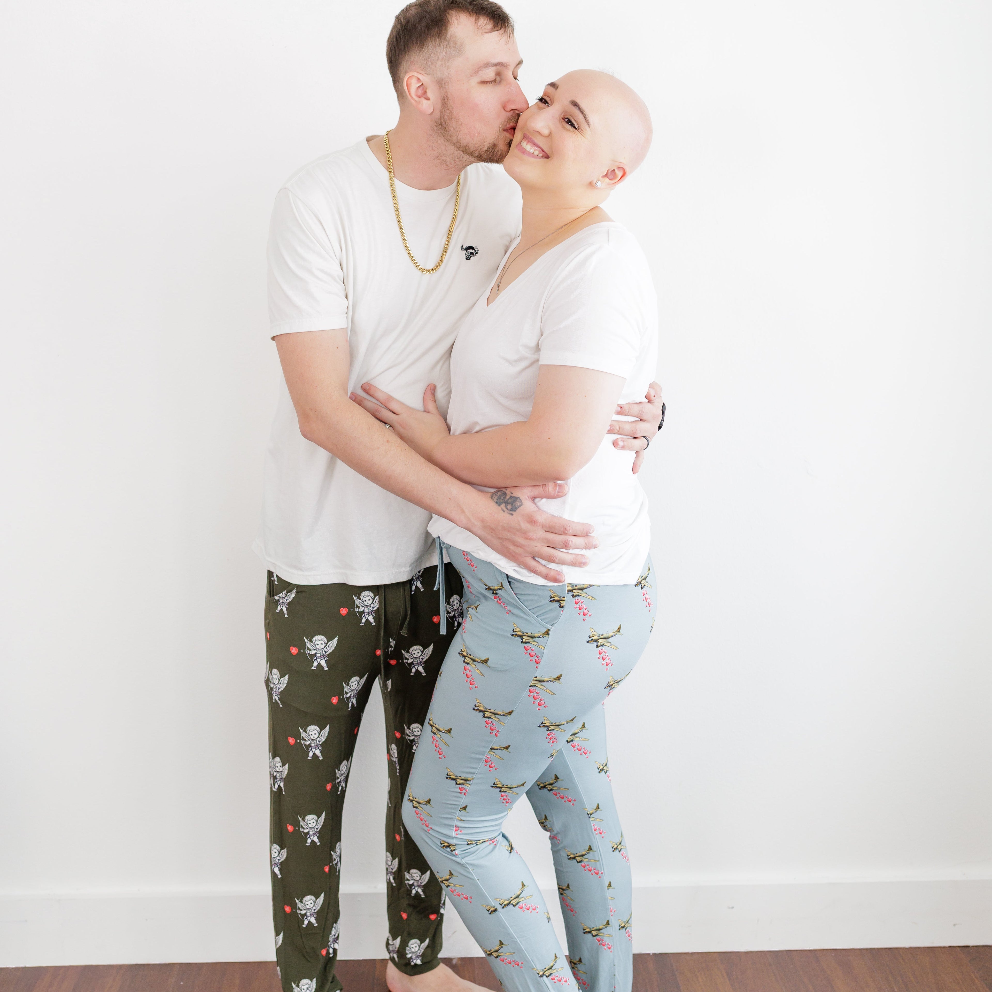 Man and woman embracing on a wooden floor with a white wall background