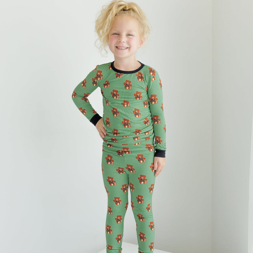 Child wearing green pajamas with animal pattern on a white surface