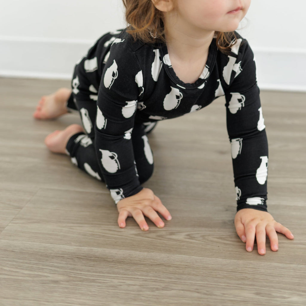 Child wearing a black outfit with white patterns on a wooden floor