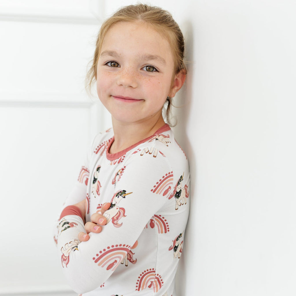 Young girl wearing a long-sleeve pajama set with animal print against a white background