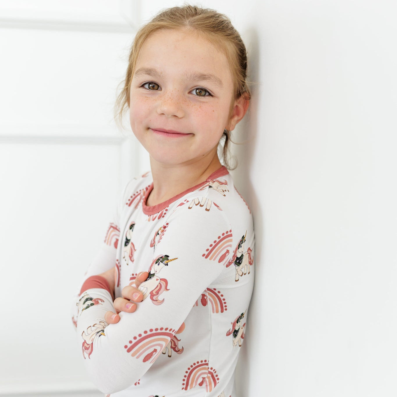 Young girl wearing a long-sleeve pajama set with animal print against a white background