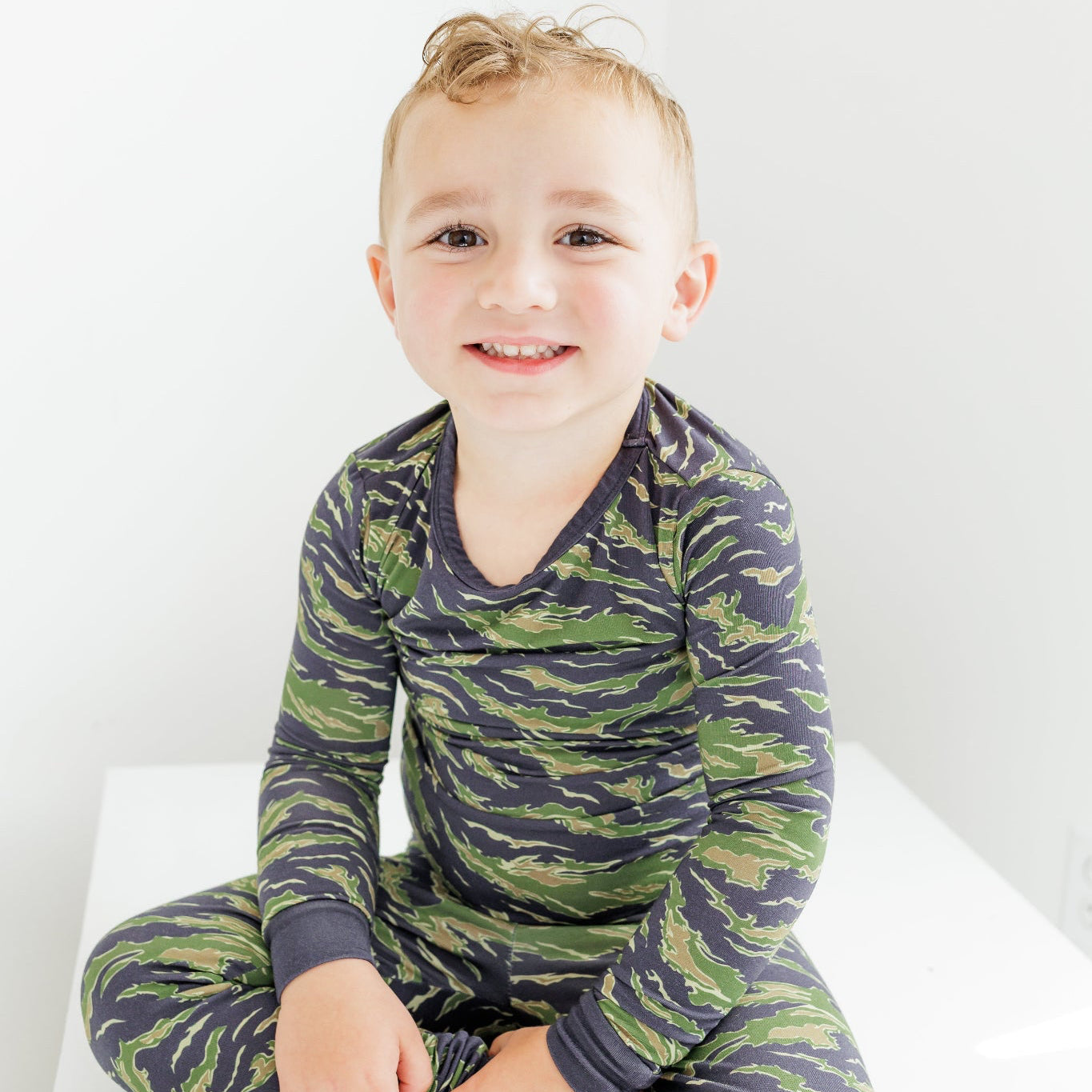 Child wearing a green and purple zebra print onesie on a white background