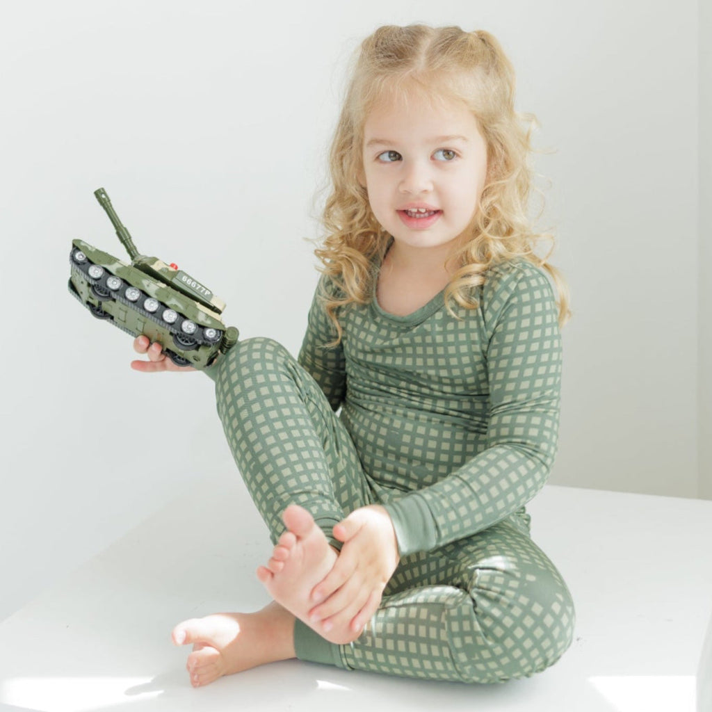 Young girl in green pajamas holding a toy on a white background