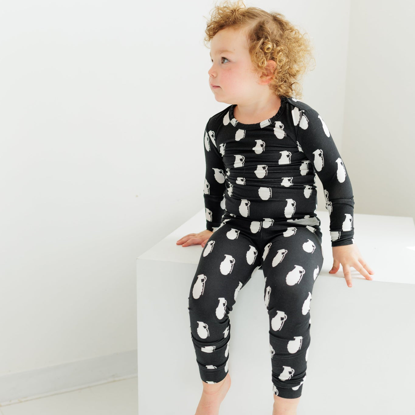 Child wearing a black pajama set with white animal prints on a white background