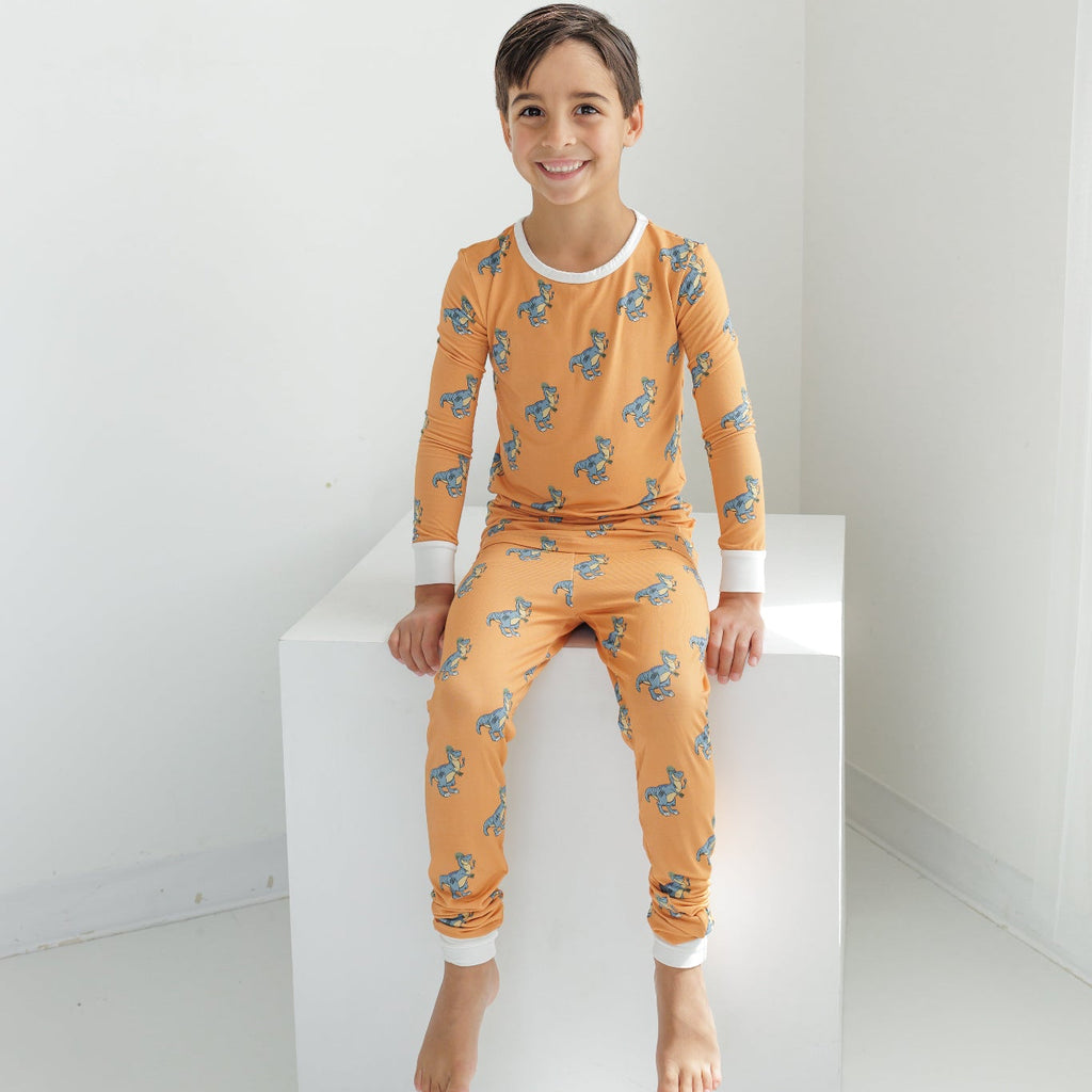 Child wearing orange pajamas with a pattern on a white background