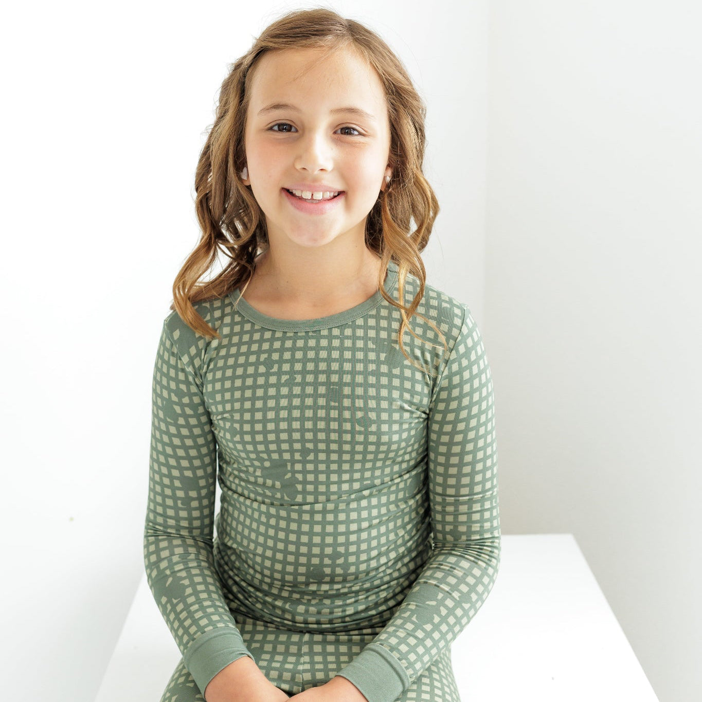 Young girl wearing a green checkered dress against a white background