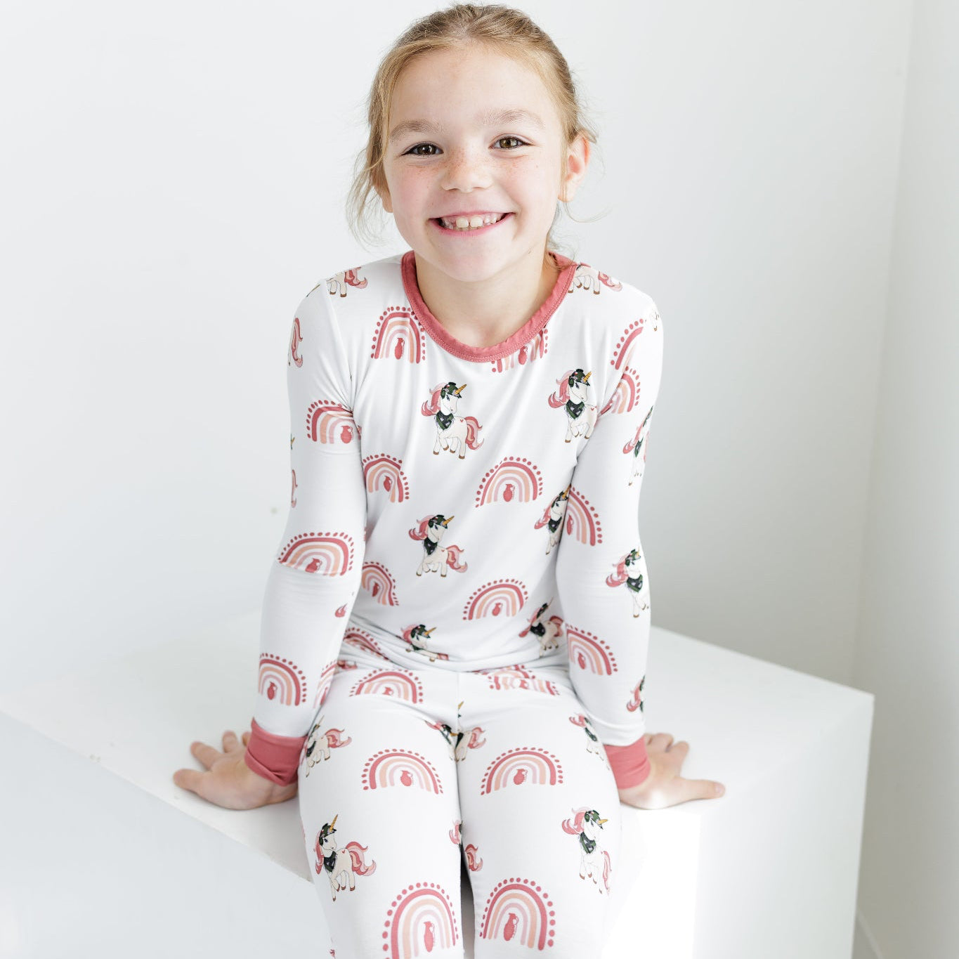 Child wearing a white pajama set with red accents and cartoon characters on a white background