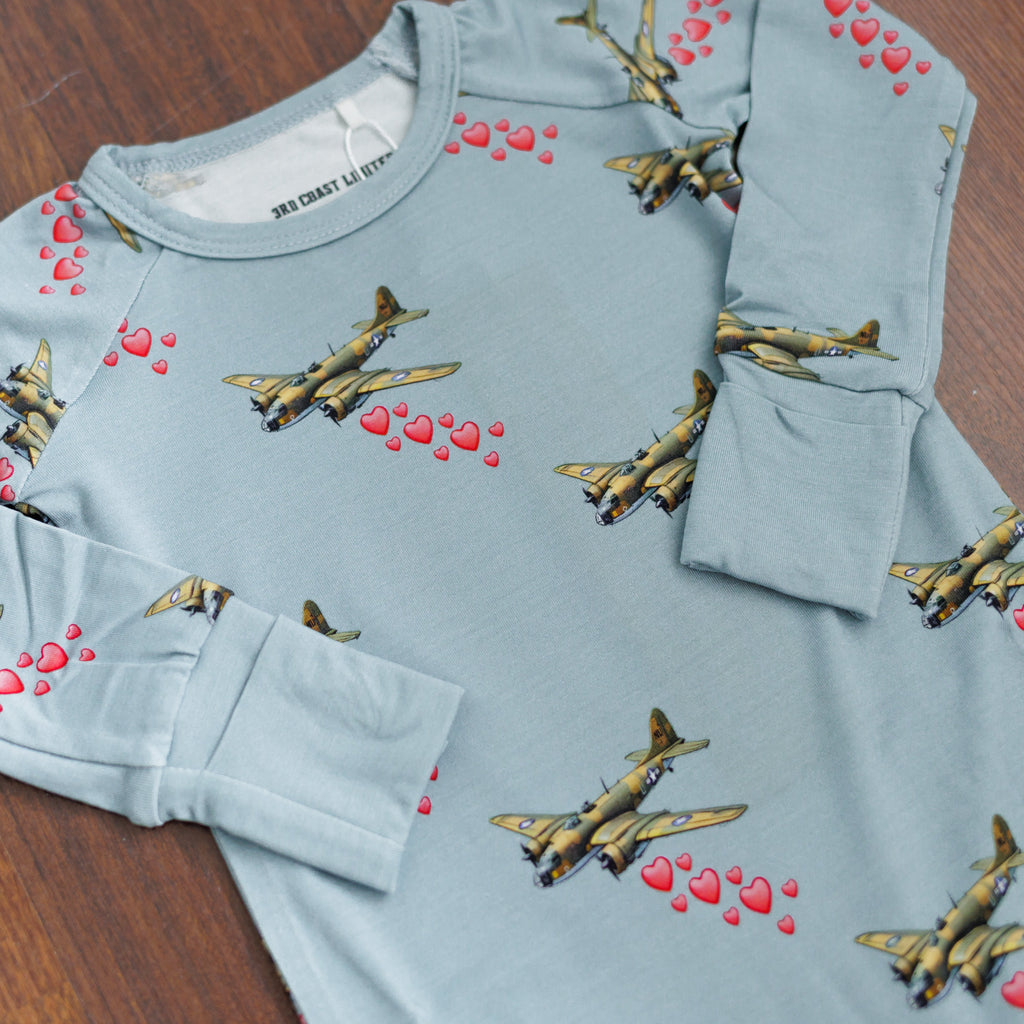 Light blue sweatshirt with airplane and heart patterns on a wooden surface