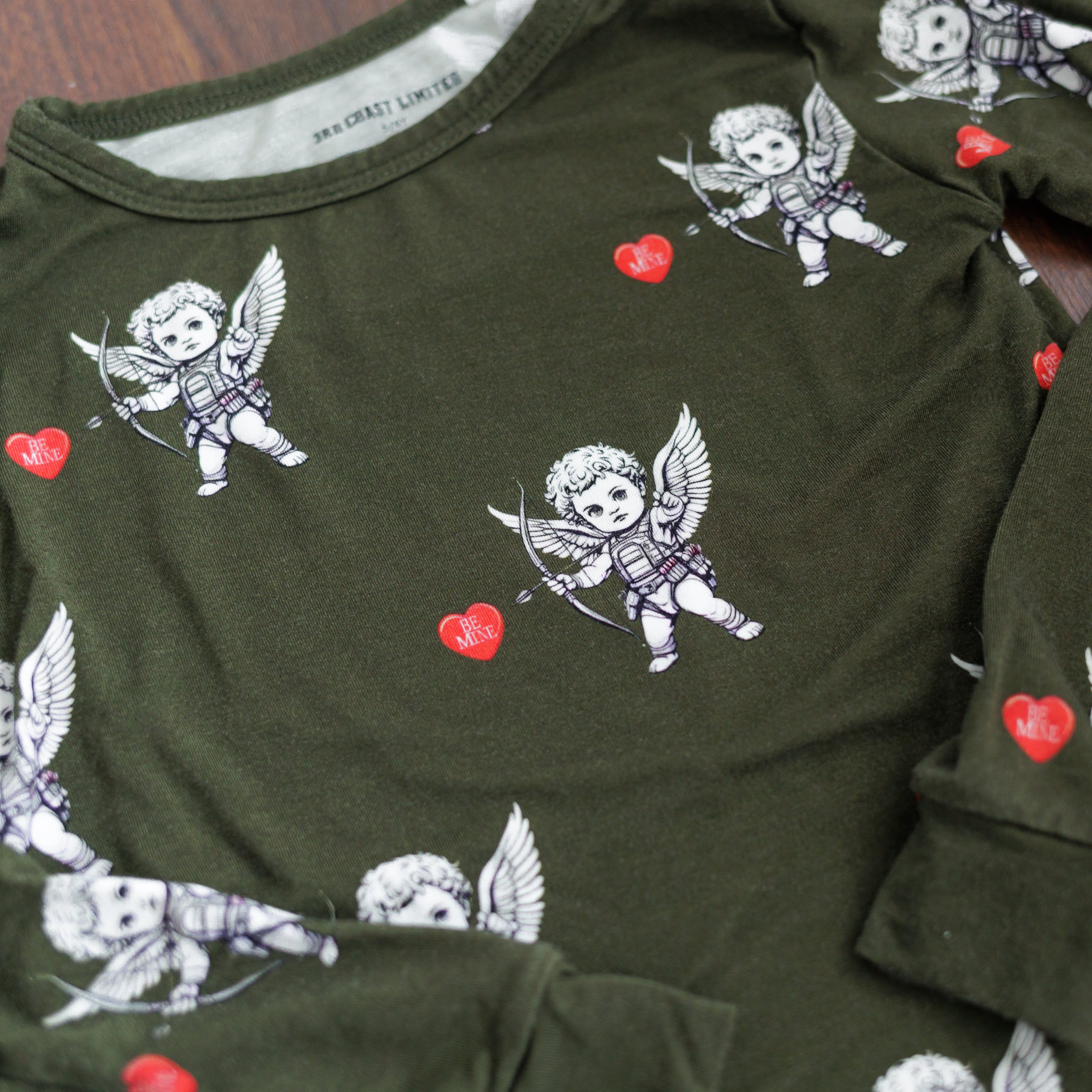 Green shirt with cupid and heart pattern on a wooden surface