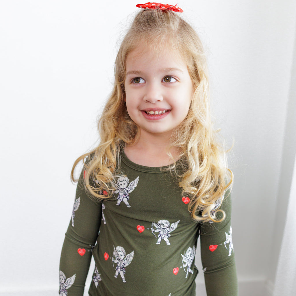 Young girl wearing a green long-sleeve shirt with fairy and heart designs on a white background
