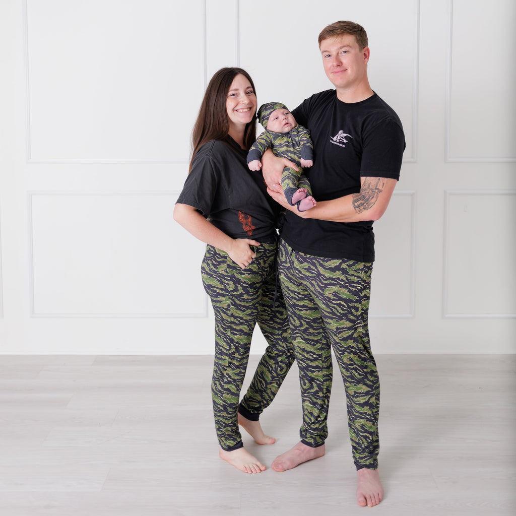 Family of three wearing matching camouflage outfits against a white background