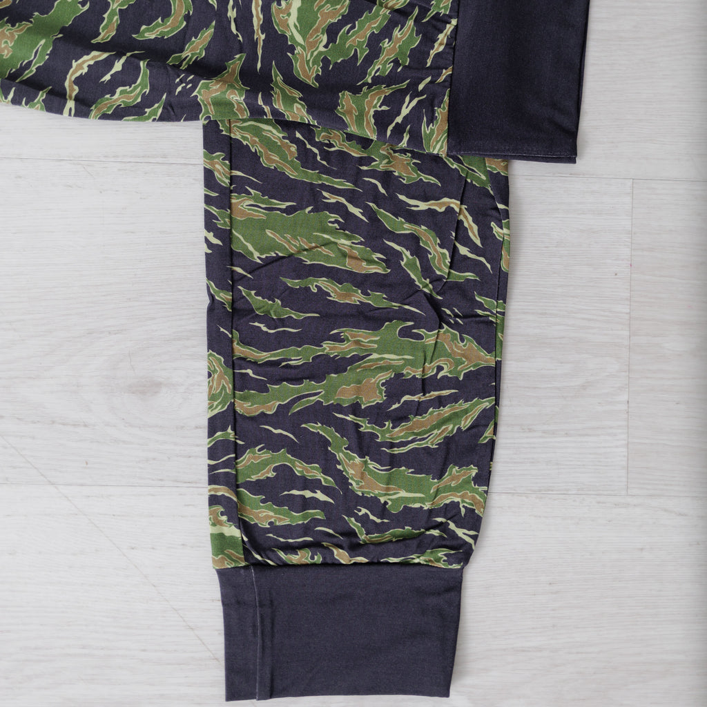 Green and navy camouflage pants on a light gray background