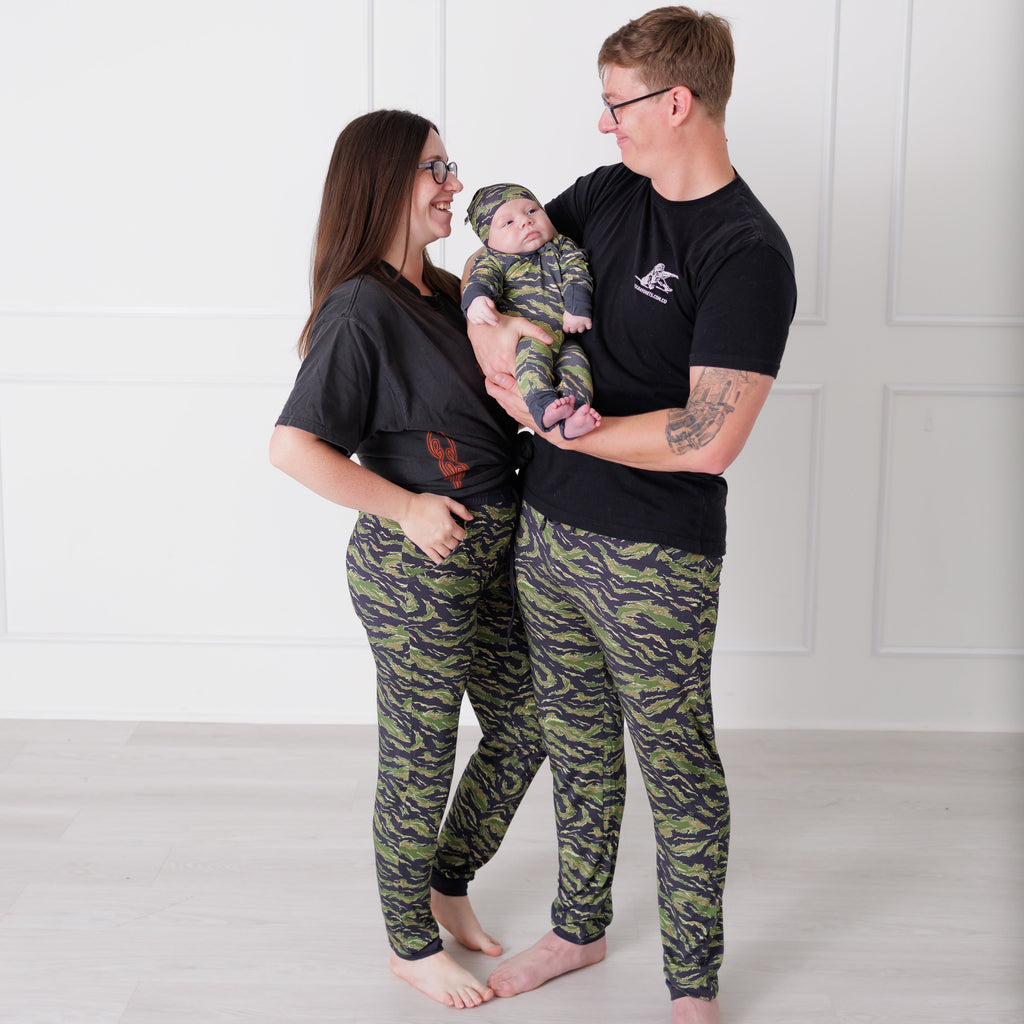 Family of three wearing matching camouflage outfits against a white background