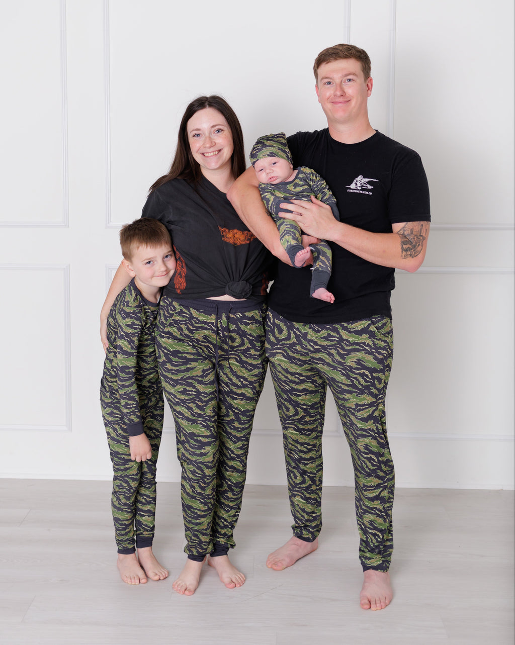 Family of four wearing matching camouflage pants against a white background