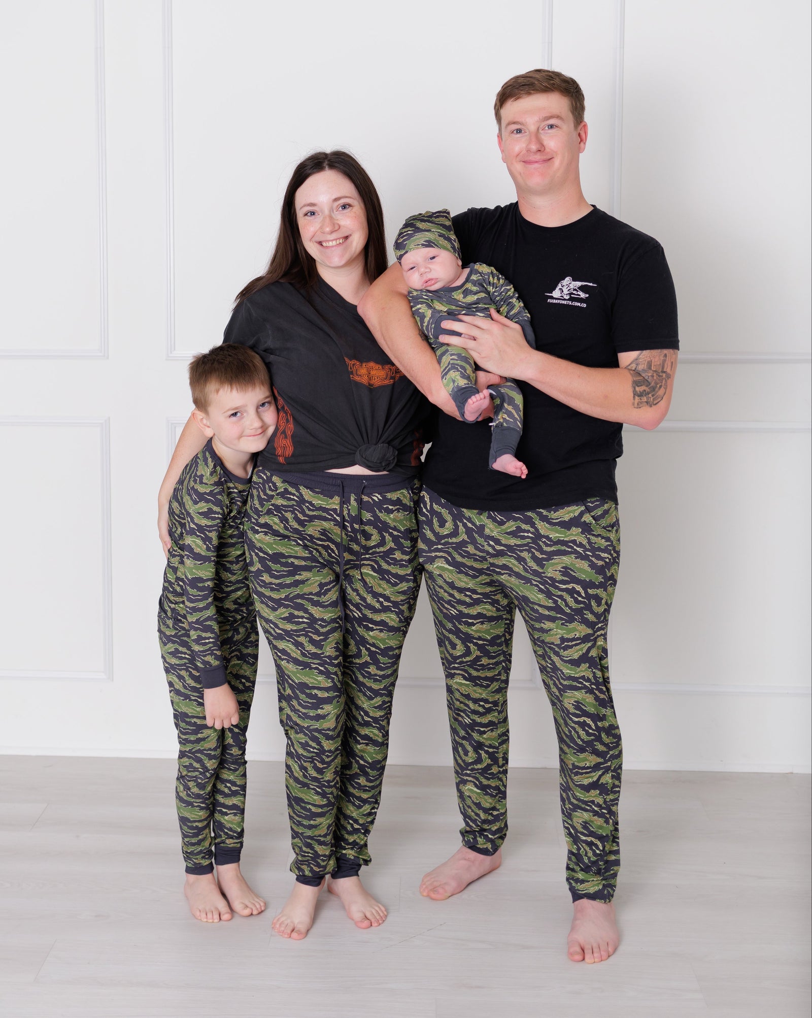 Family of four wearing matching camouflage pants against a white background