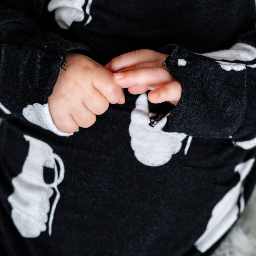 Person wearing a black and white patterned outfit on a white fluffy blanket