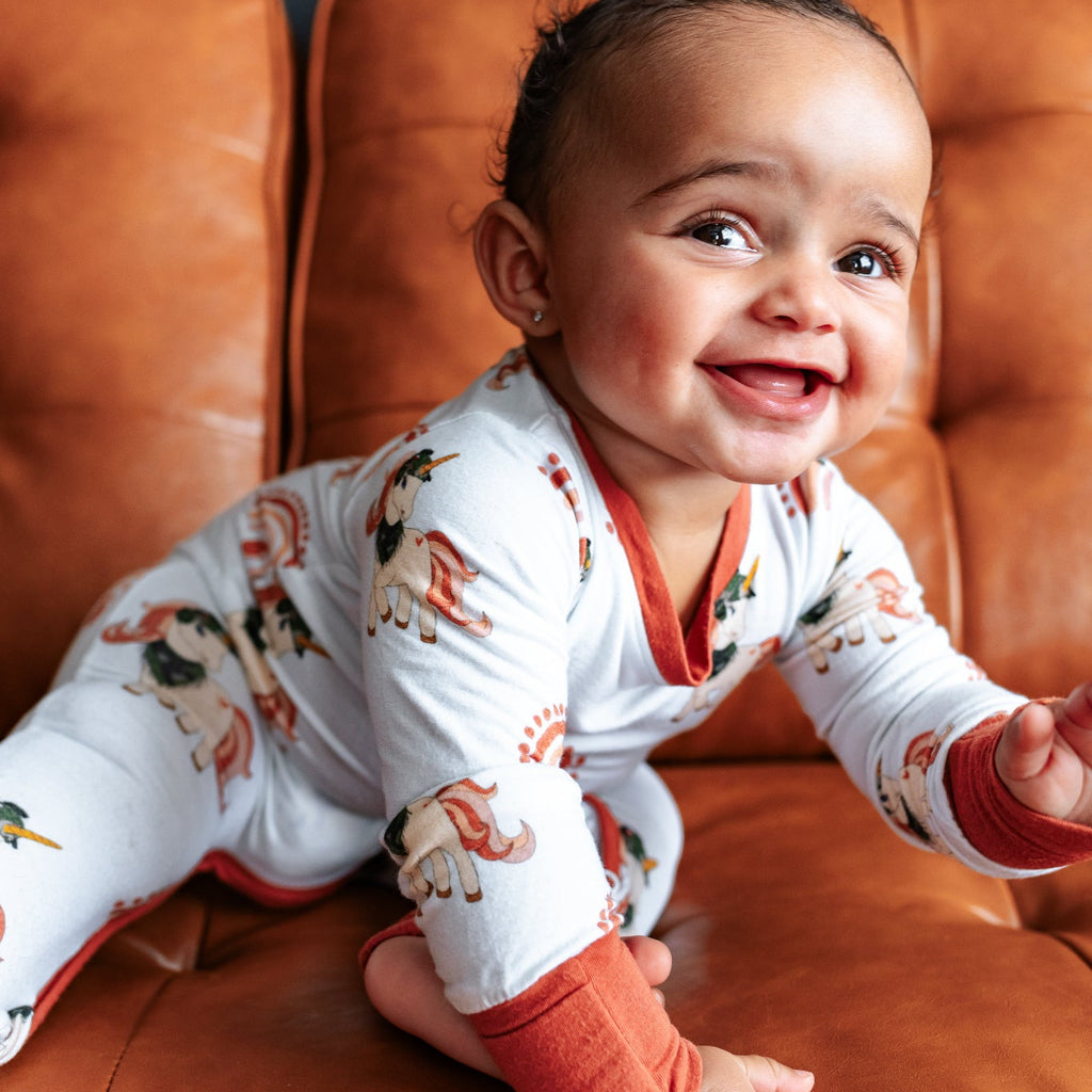 Baby in pajamas sitting on a brown leather couch