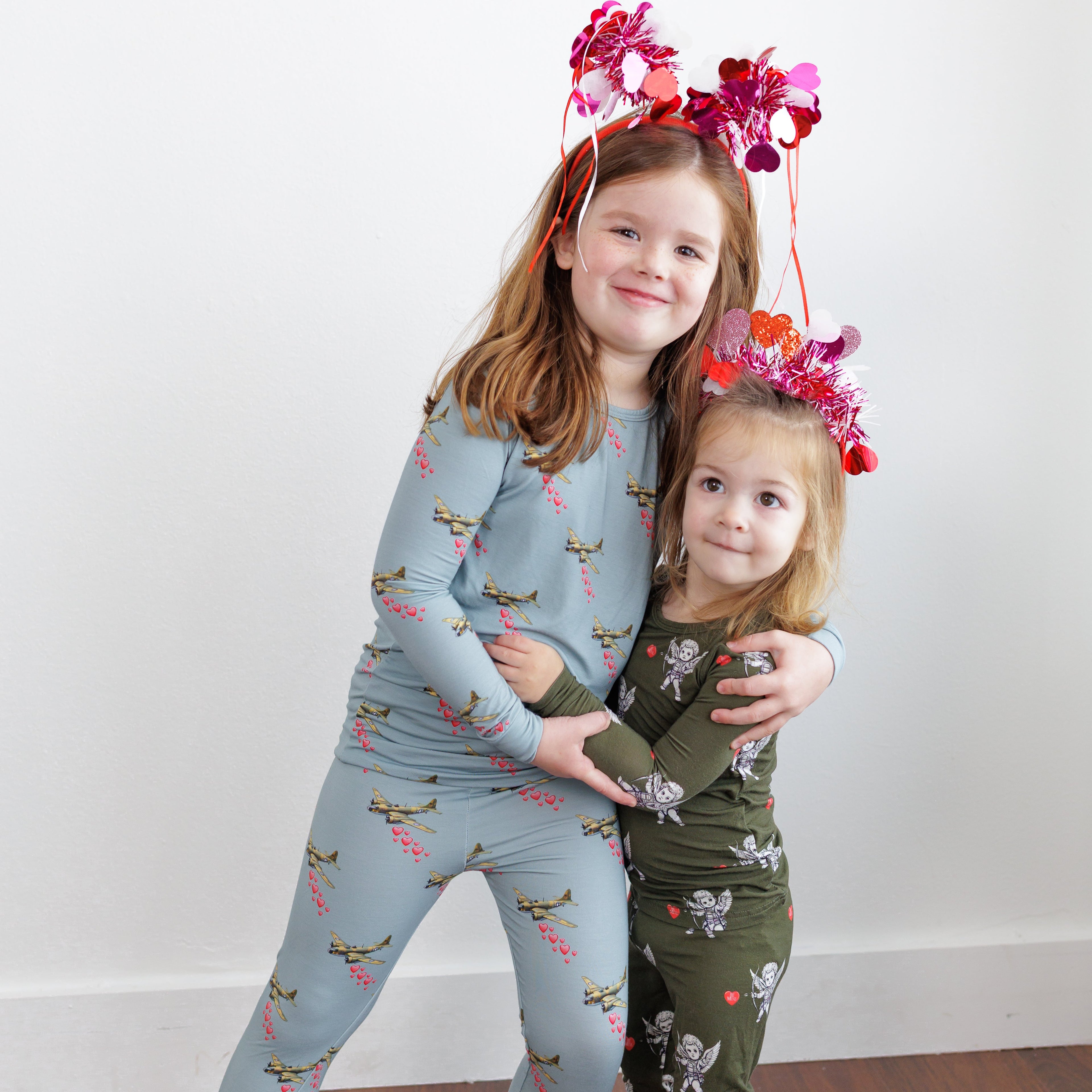 Two children wearing matching pajamas with a plain white background