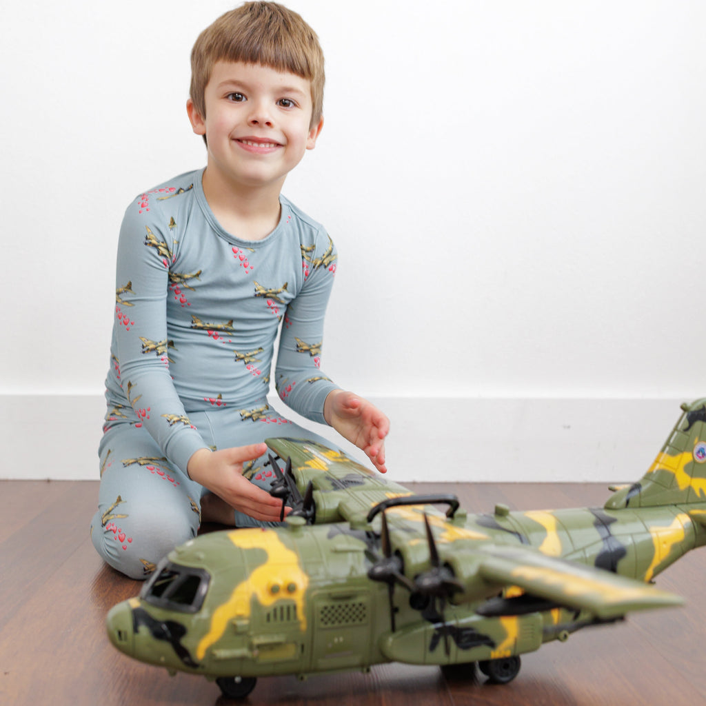 Child playing with a toy helicopter on a wooden floor.