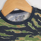 Close-up of a camo baby romper by 3rd Coast Limited, showing the green and brown tiger stripe pattern with navy trim and the inner neck label reading ‘95% Bamboo 5% Spandex – Made in India.