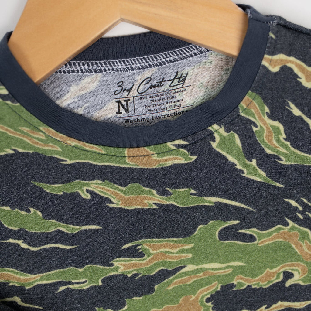 Close-up of a camo baby romper by 3rd Coast Limited, showing the green and brown tiger stripe pattern with navy trim and the inner neck label reading ‘95% Bamboo 5% Spandex – Made in India.